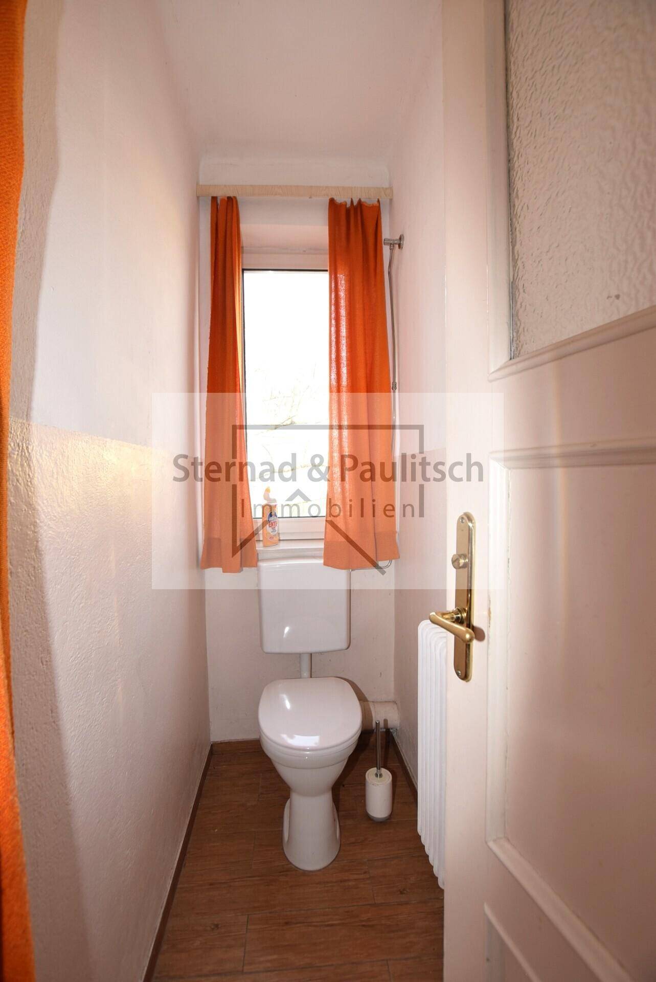 Schlichtes WC mit Fenster, Toilette und Heizkörper.