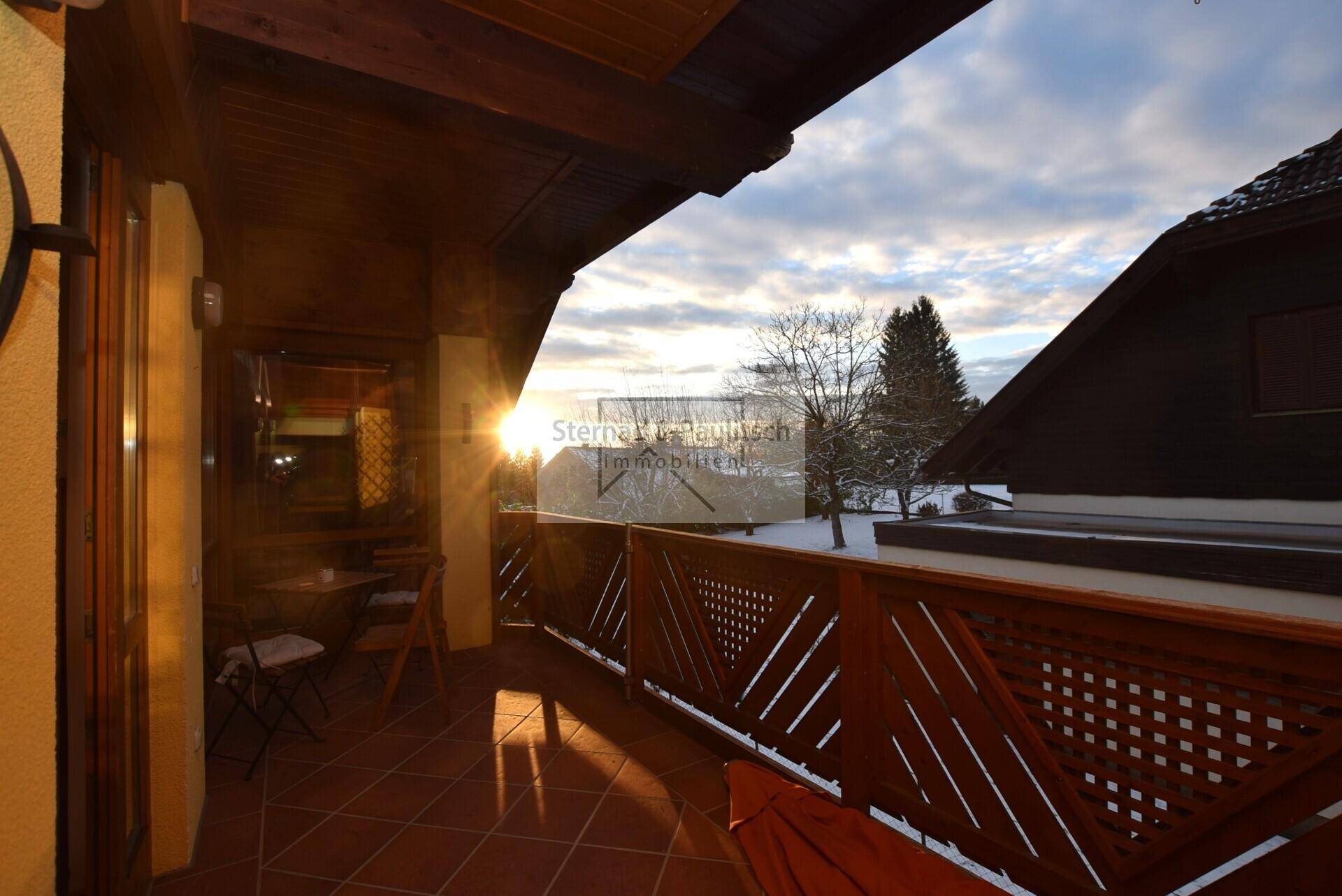 Überdachter Balkon mit Fliesenboden und Holzbalken, bietet einen weiten Blick über die Landschaft.