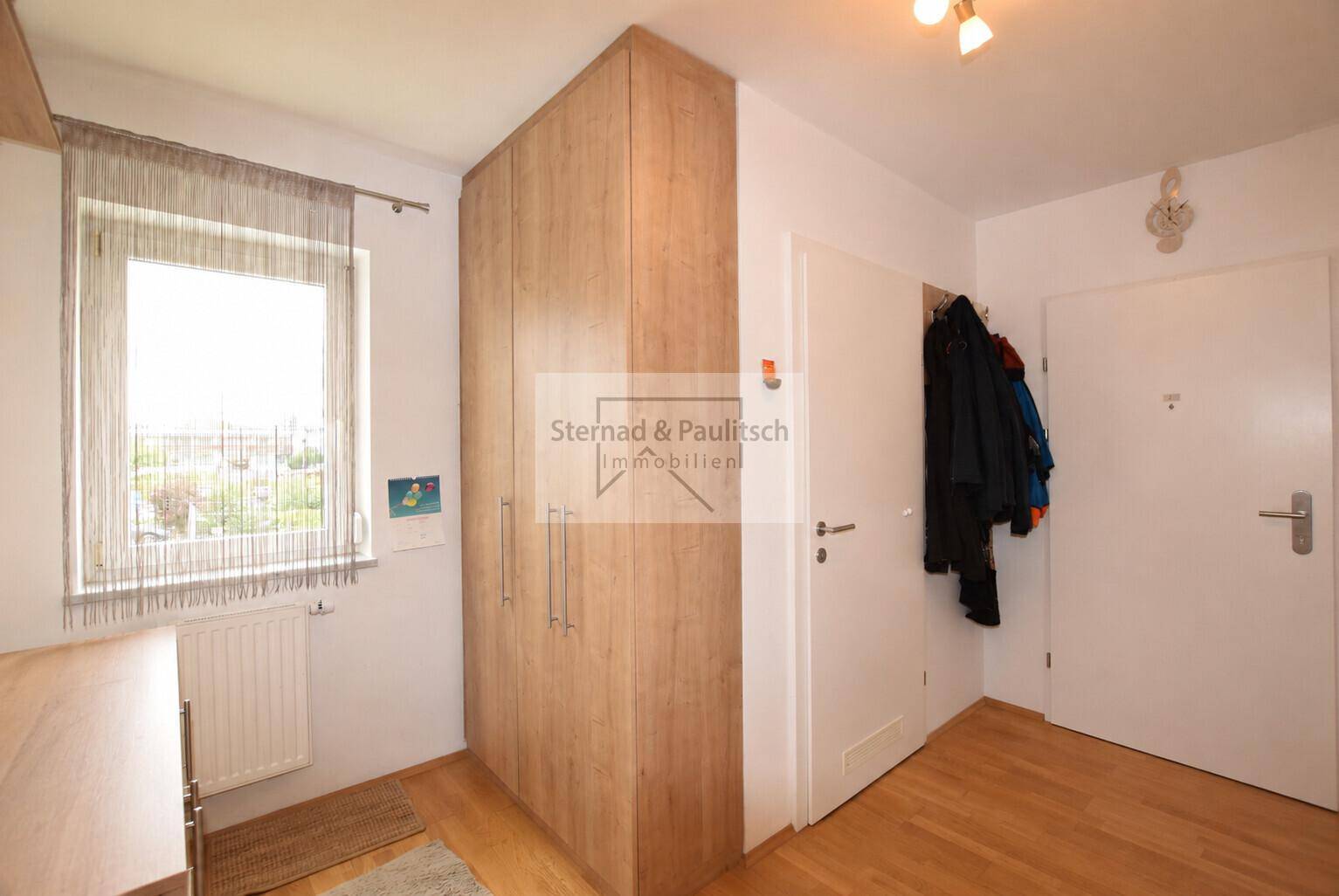 Schlafzimmer mit Holzboden und großem Kleiderschrank, bietet direkten Zugang zum Flur.