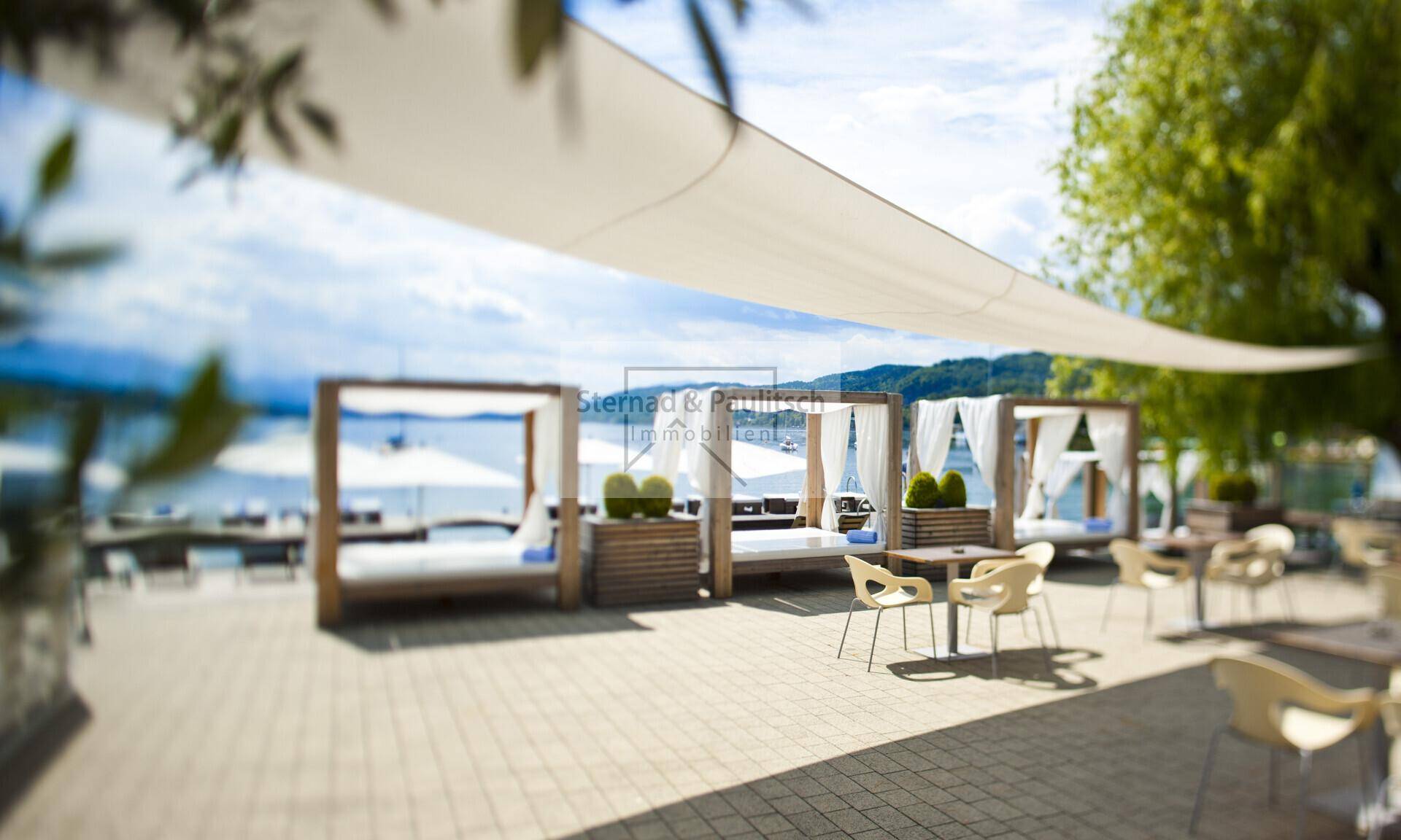Exklusiver Außenbereich mit luxuriösen Tagesbetten und Sitzgelegenheiten direkt am Seeufer.