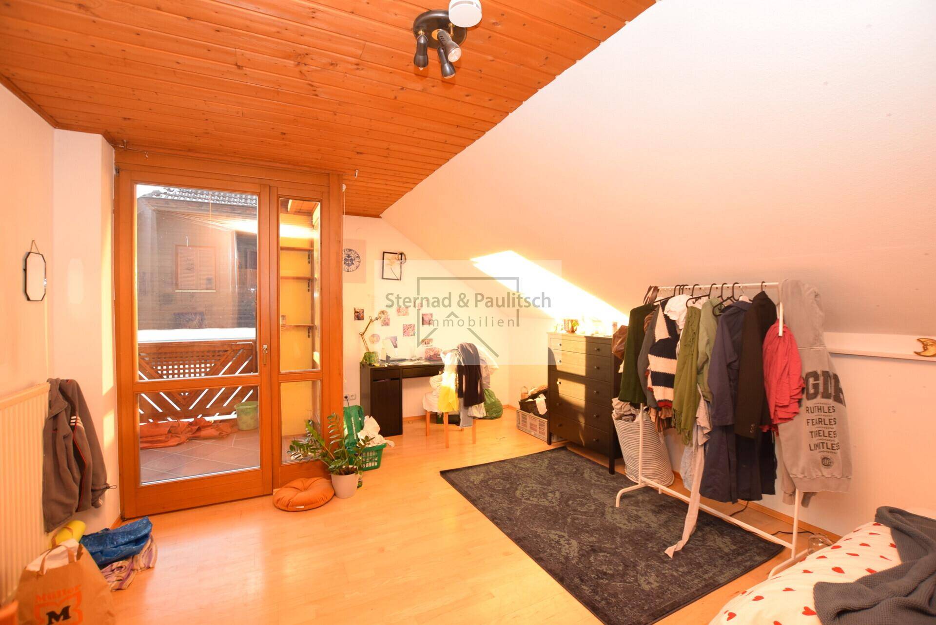 Schlafzimmer mit Holzboden und Zugang zu einem Balkon, hell und mit viel Tageslicht.