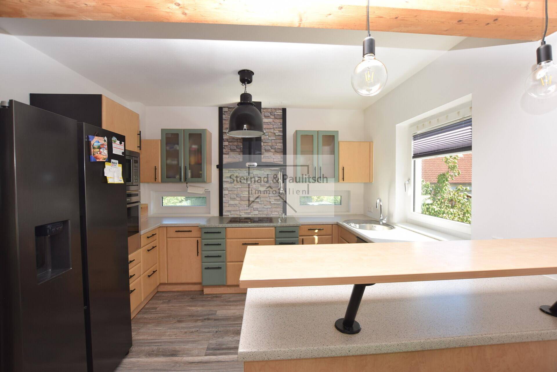 Geräumige Küche mit Frühstücksbar, Holzschränken und Blick nach draußen.