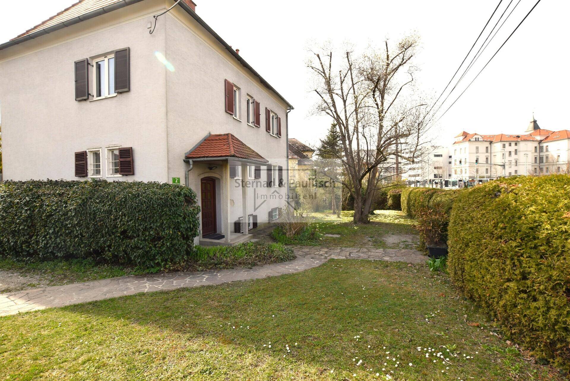 Vorderansicht des Hauses mit gepflegter Hecke und Zugang zum Eingangsbereich.
