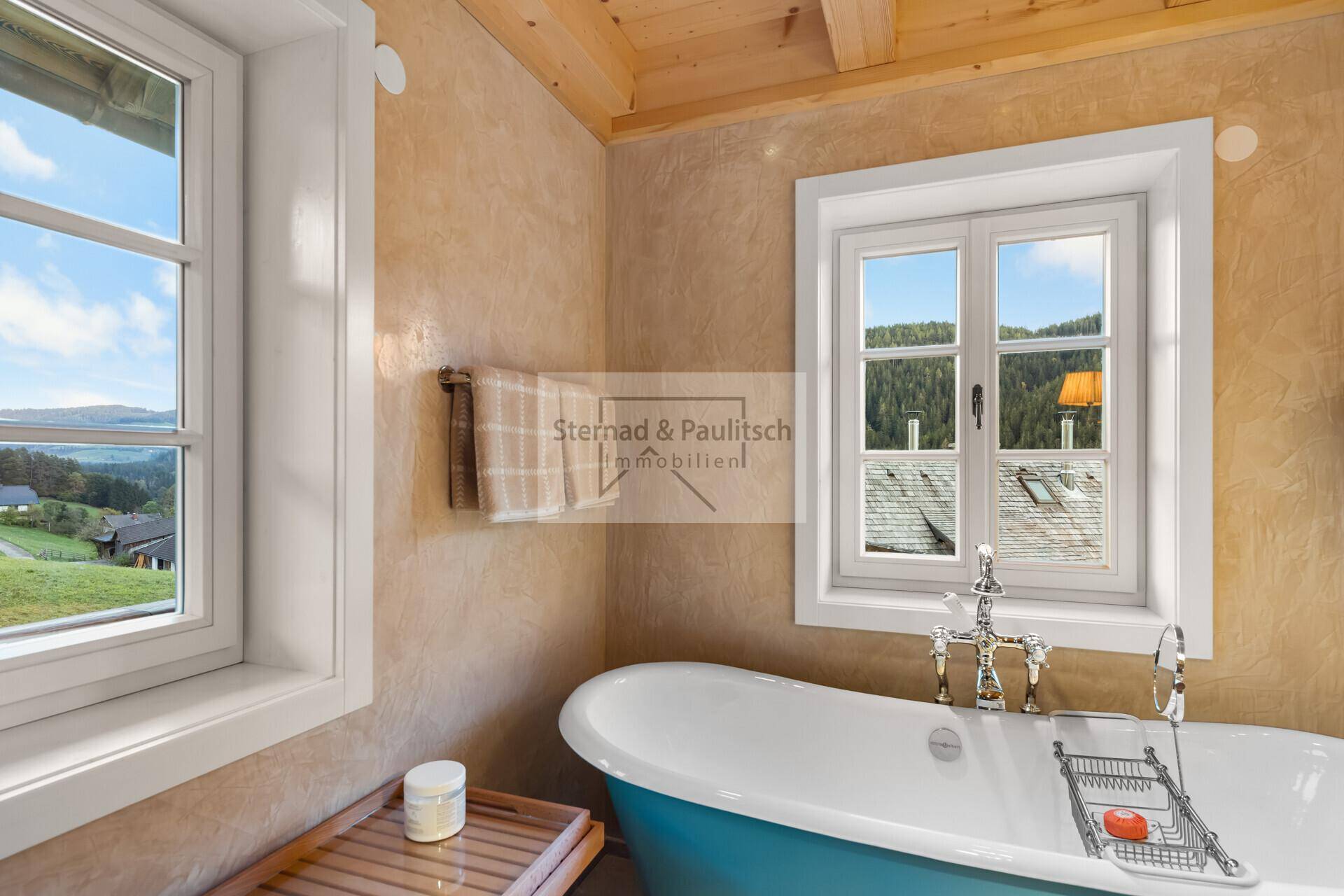 Detailansicht der freistehenden blauen Badewanne im Badezimmer mit Ausblick auf die grüne Landschaft.
