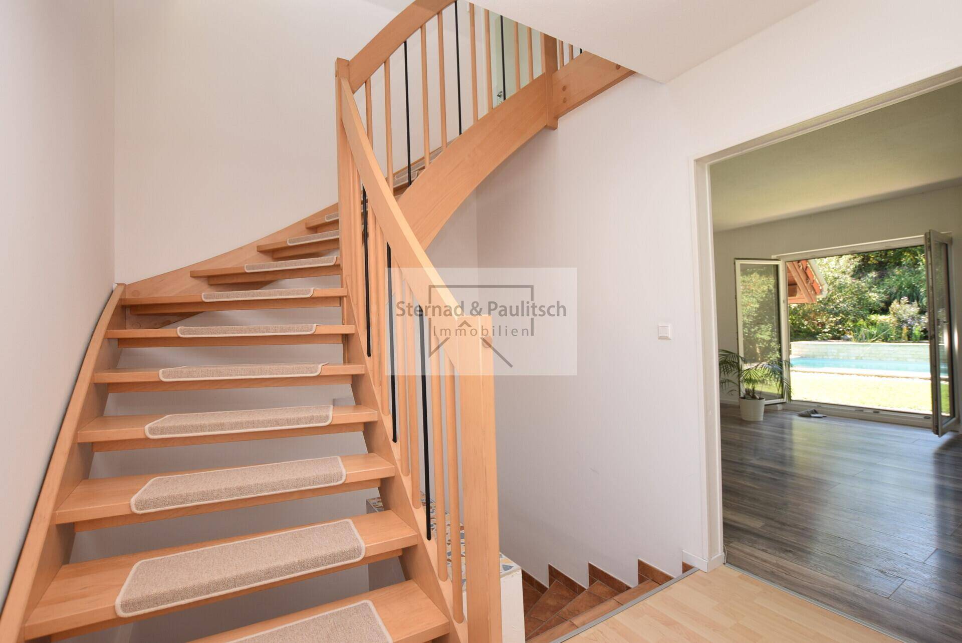 Elegante Holztreppe mit Teppichläufern verbindet die Stockwerke des Hauses.