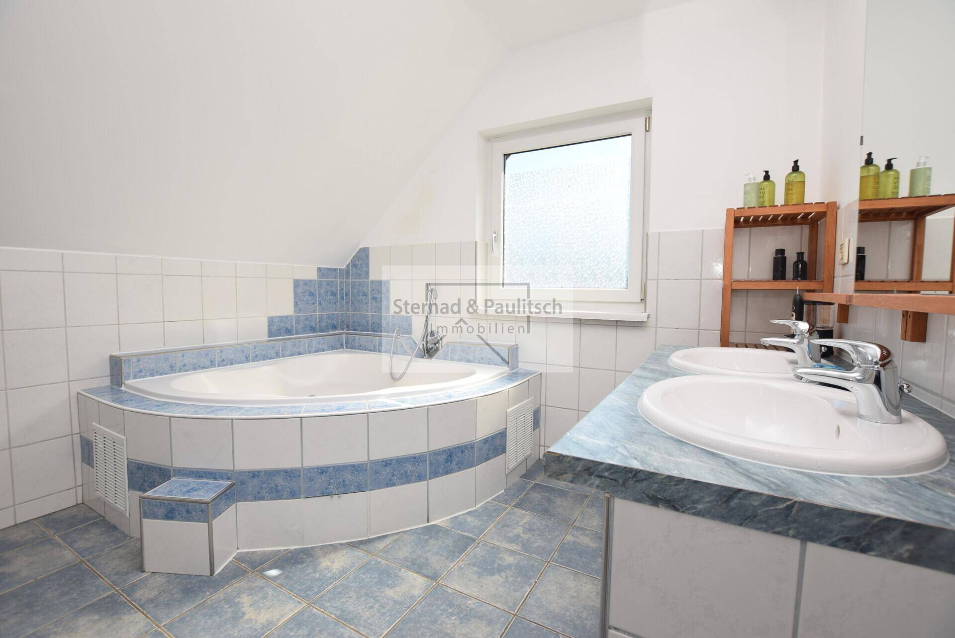 Geräumiges Badezimmer mit Eckbadewanne, Doppelwaschbecken und Fenster.