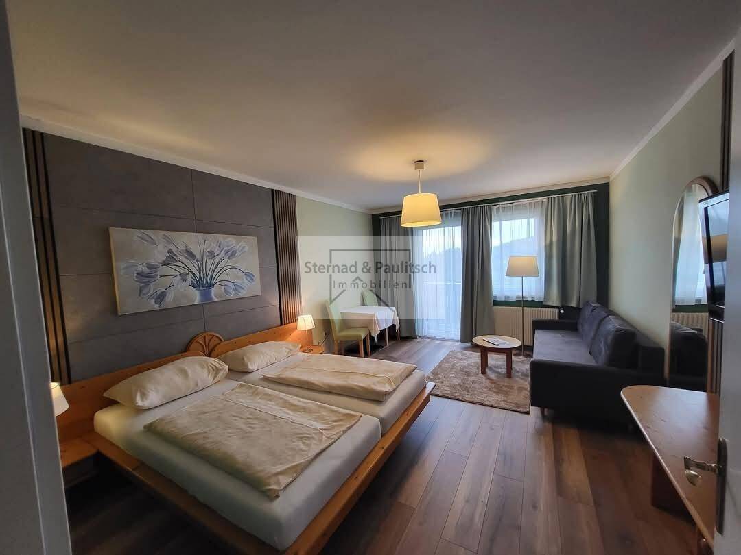 Helles Schlafzimmer mit Doppelbett, Sofa und Zugang zu einem Balkon oder Terrasse.