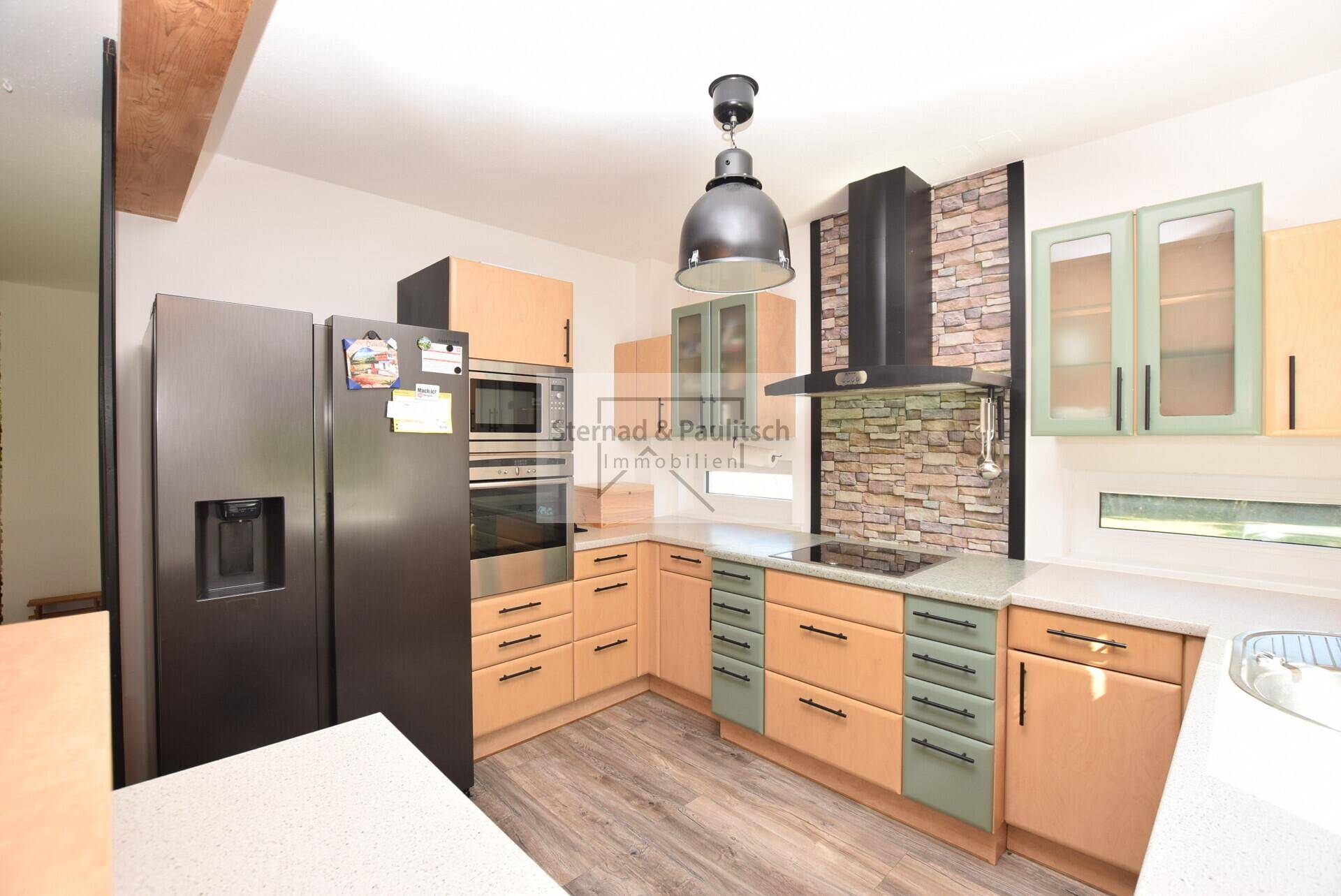 Funktionale Küche mit Holzschränken, integrierten Geräten und Steinwand-Akzent.