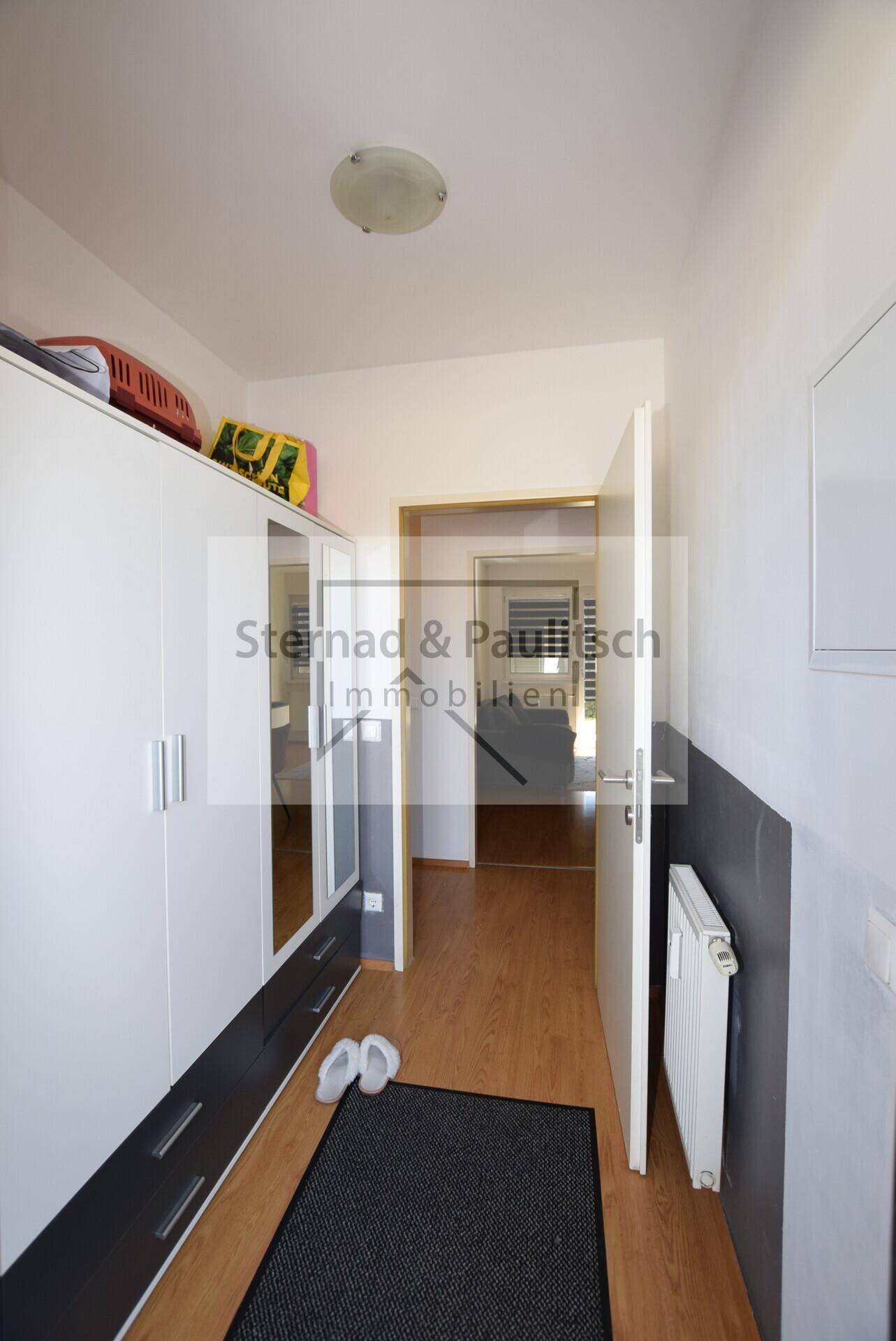 Eingangsbereich mit Garderobenschrank, Spiegel und Laminatboden.