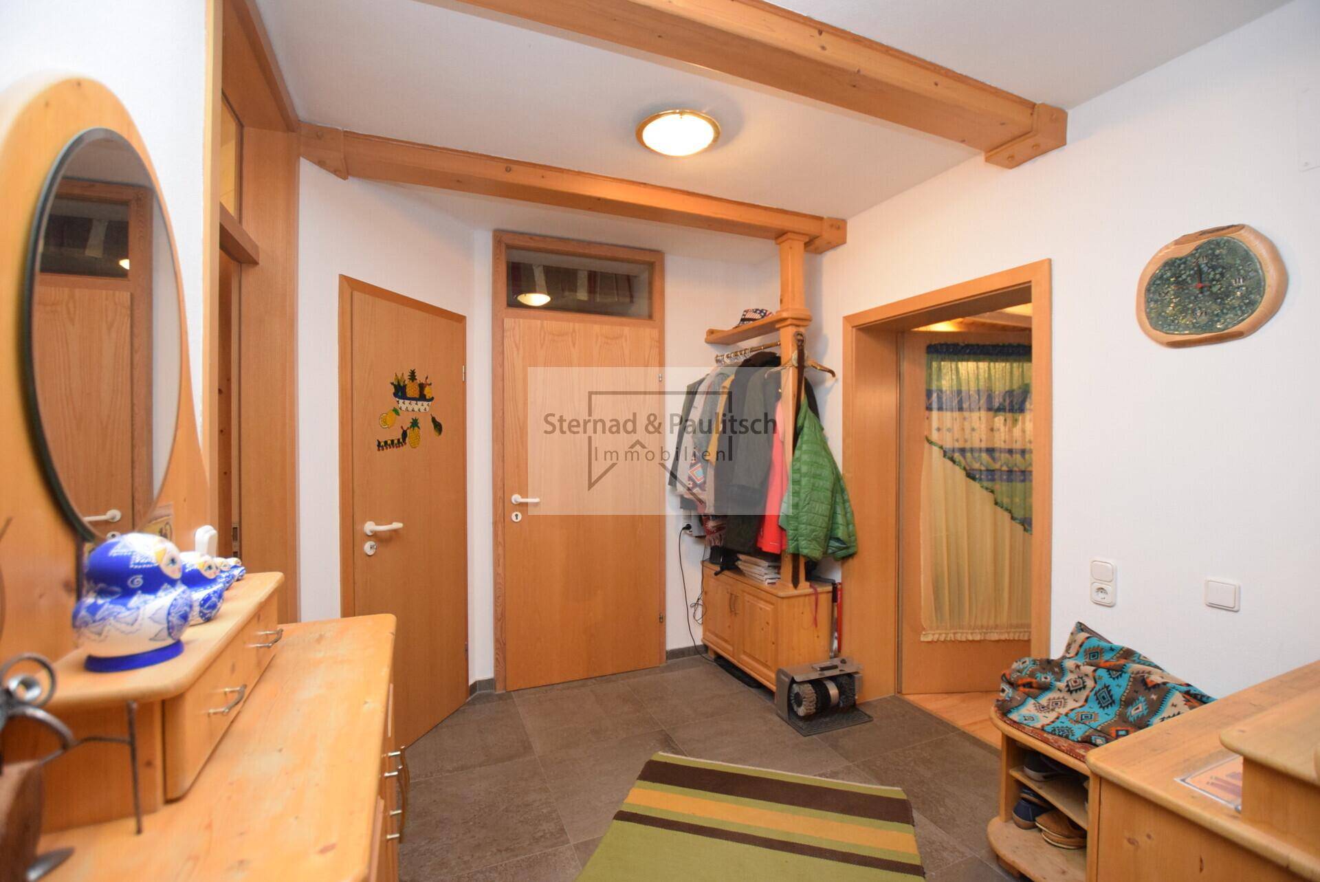 Heller Flur mit Steinboden, Holzbalken und rustikalen Holzmöbeln, einladender Eingangsbereich.