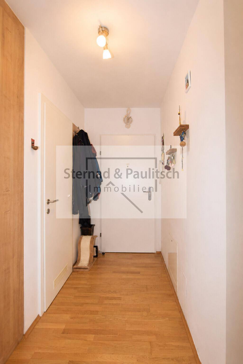 Heller Eingangsbereich mit Holzboden und Garderobe, führt zu den verschiedenen Wohnbereichen.