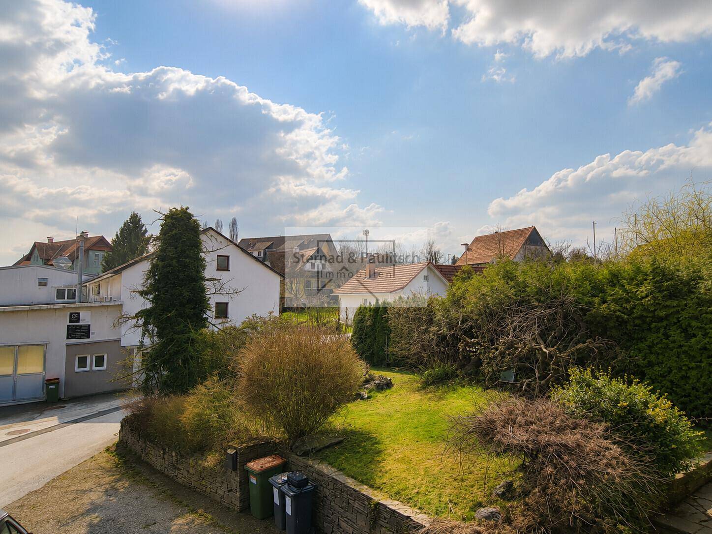 Blick auf den eigenen Garten und die umliegende Nachbarschaft unter blauem Himmel.