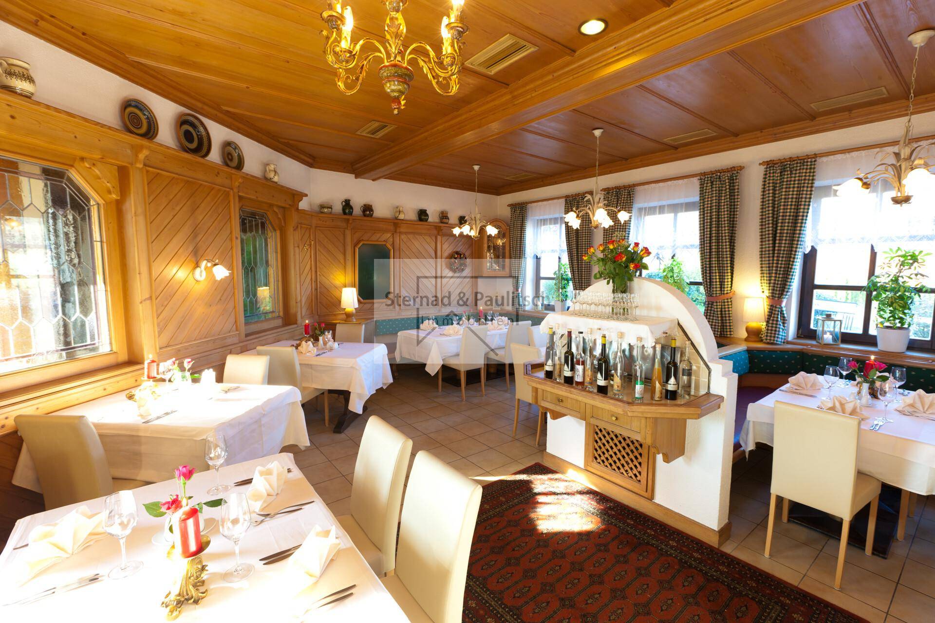 Rustikaler Speisesaal mit Holzvertäfelung, traditionellen Möbeln und gedeckten Tischen.