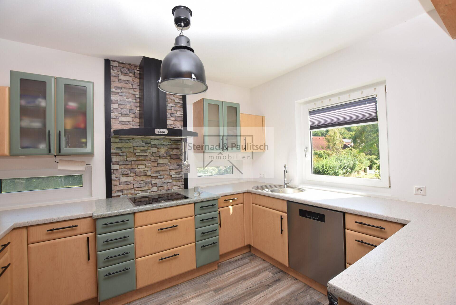 Gut ausgestattete Küche mit Spülmaschine, Kochfeld und praktischen Arbeitsflächen.