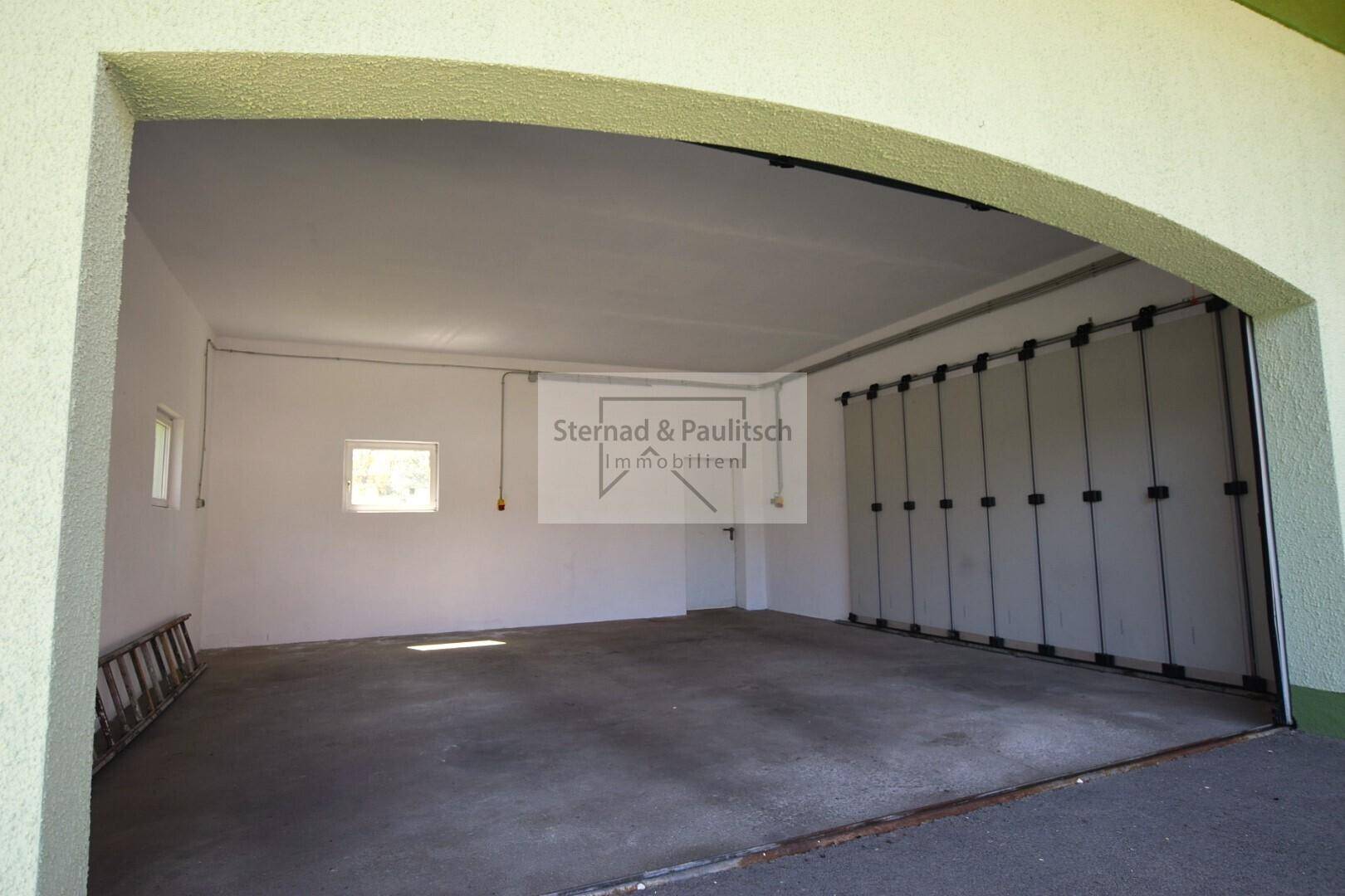 Geräumige Garage mit Betonboden und ausreichend Platz für Fahrzeuge und Lagerung.