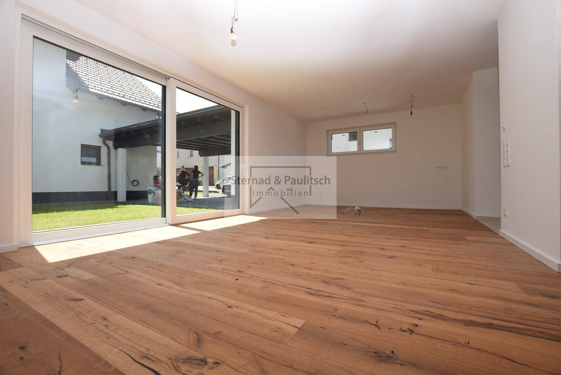 Geräumiger, unmöblierter Küchenbereich mit Holzboden und großen Schiebetüren zur Terrasse.