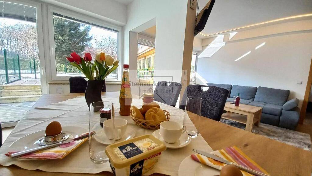 Einladender Essbereich mit gedecktem Tisch, Blumen und Blick auf den Wohnbereich, ideal für Frühstück.