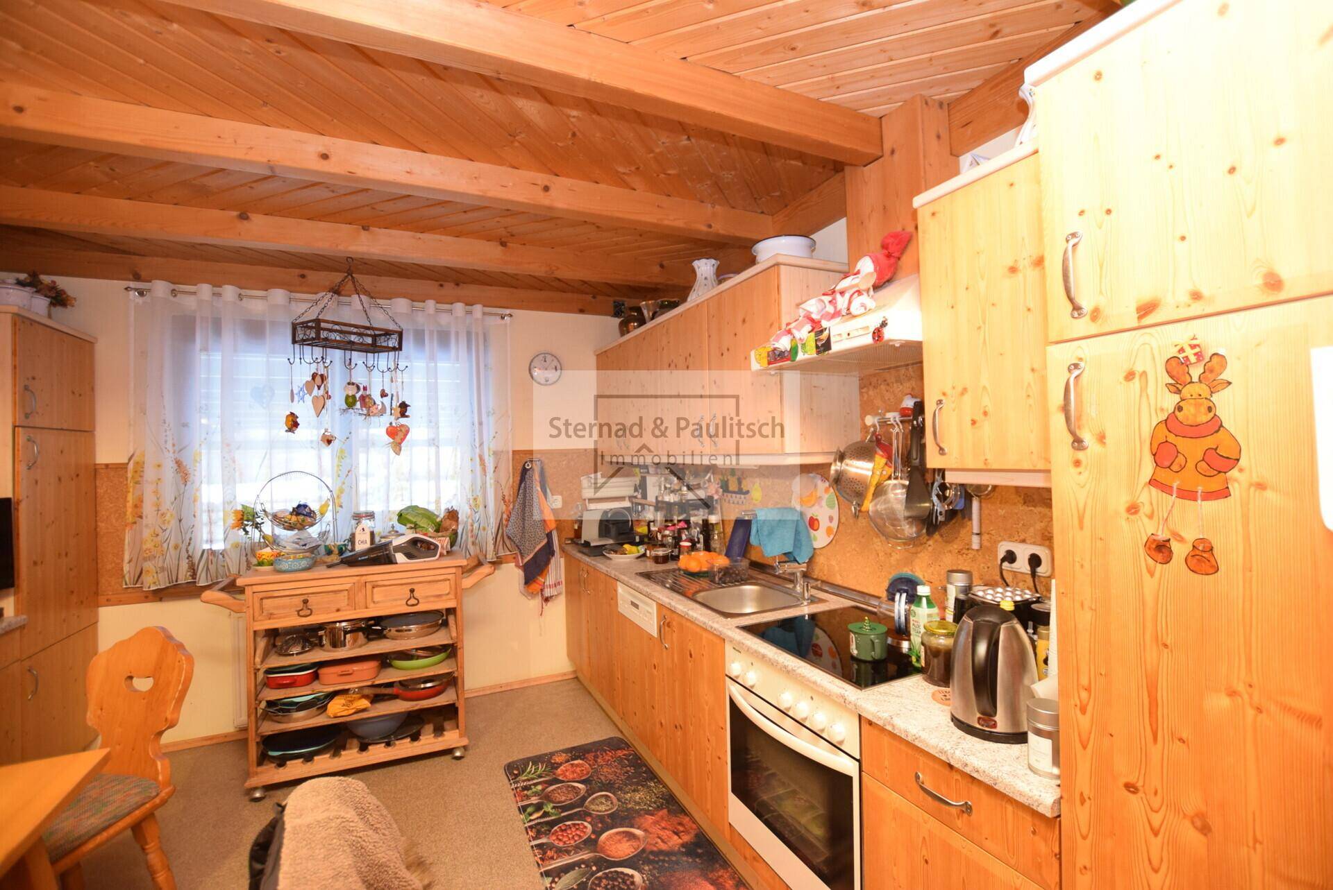 Gemütliche Küche mit Holzschränken, integrierten Geräten und Blick auf den Garten.