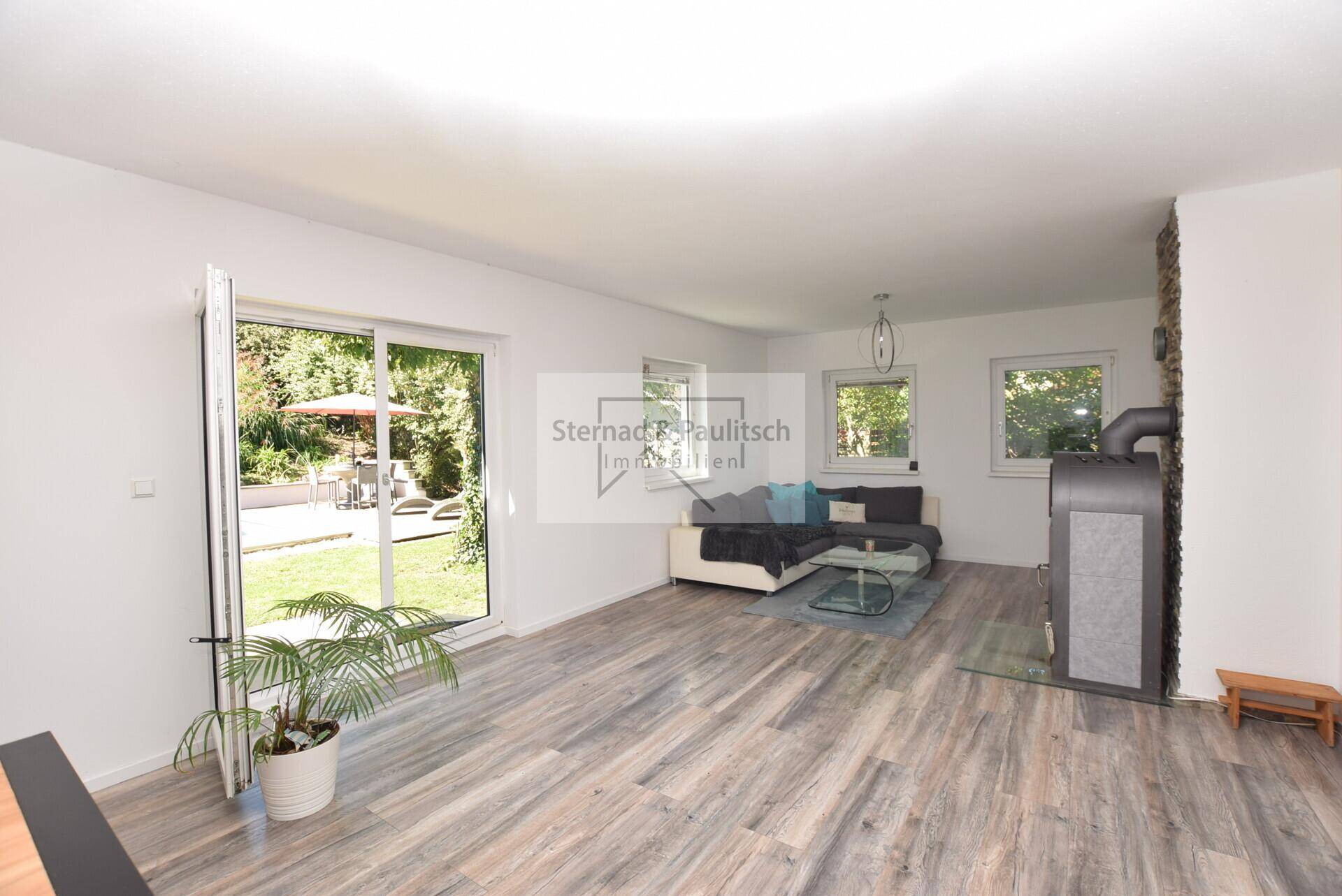 Helles Wohnzimmer mit Zugang zum Garten, Laminatboden und Blick ins Grüne.