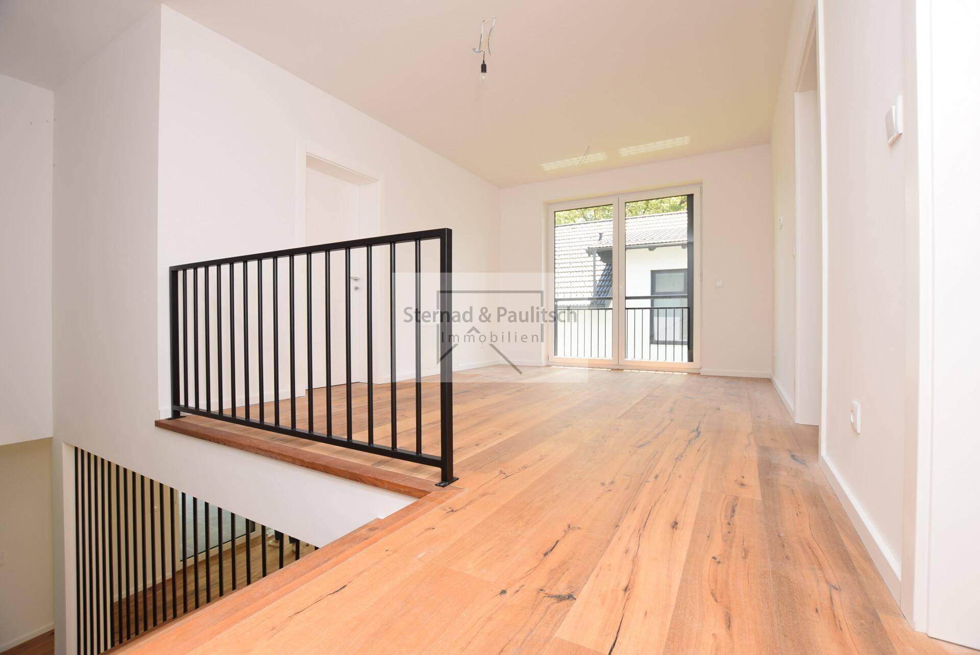 Heller Treppenabsatz mit Holzboden und Zugang zu einem französischen Balkon.