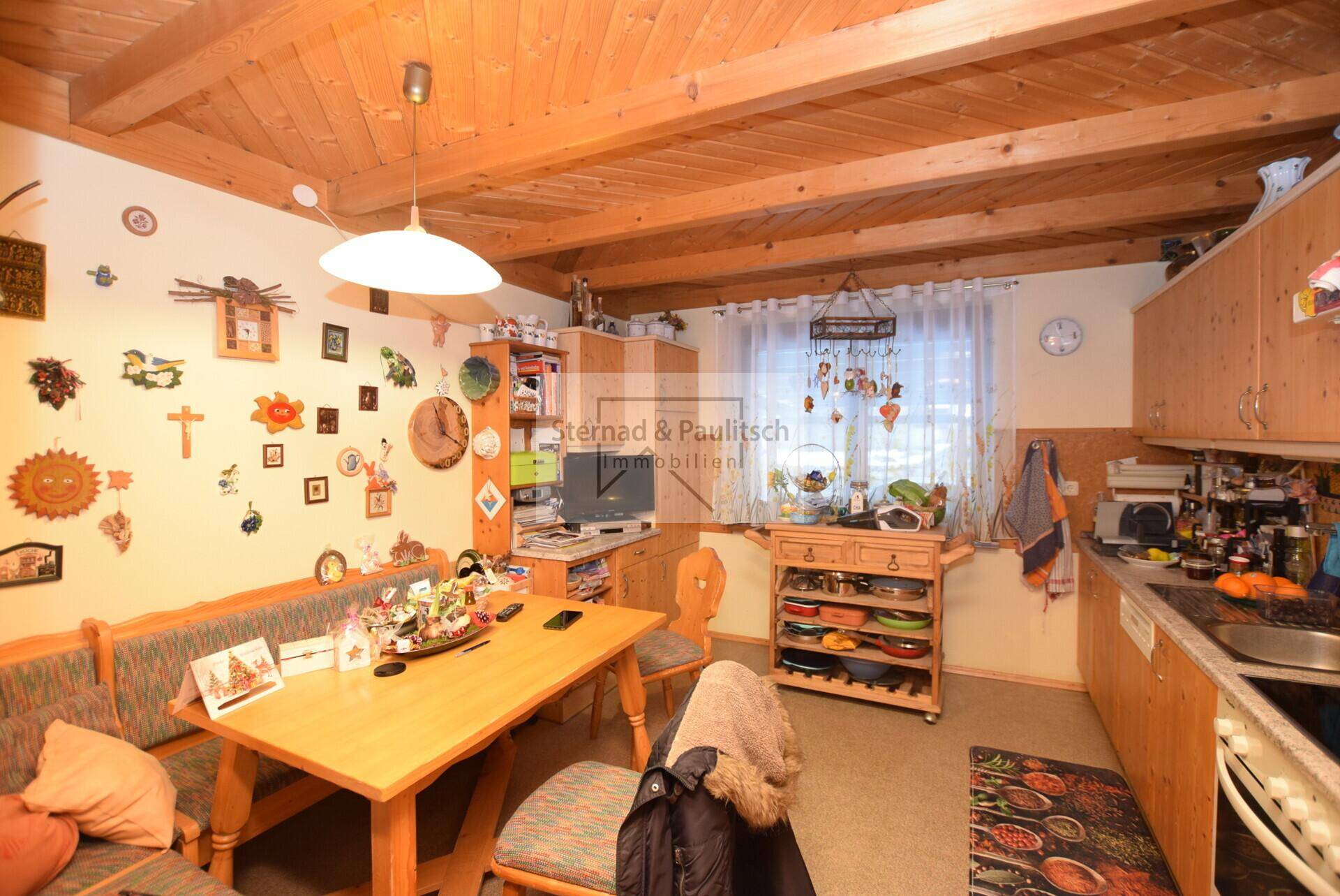 Rustikale Wohnküche mit Holzbalkendecke, Essecke und traditionellen Holzmöbeln.