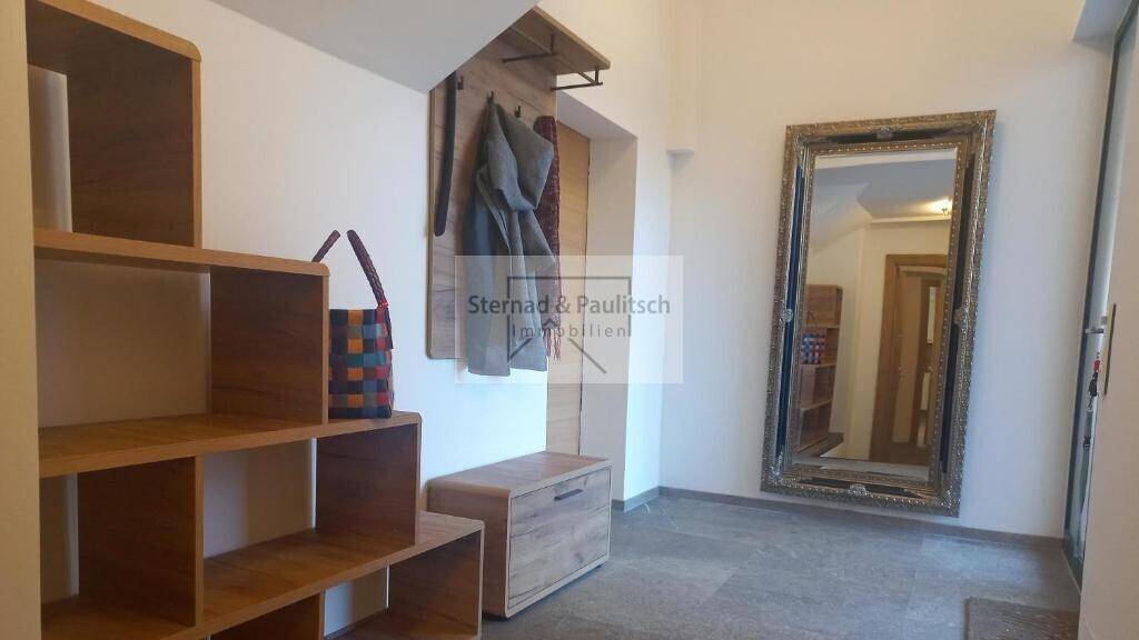 Heller Flur mit Garderobe, Spiegel und Holzregalen für Stauraum, einladend und funktional.