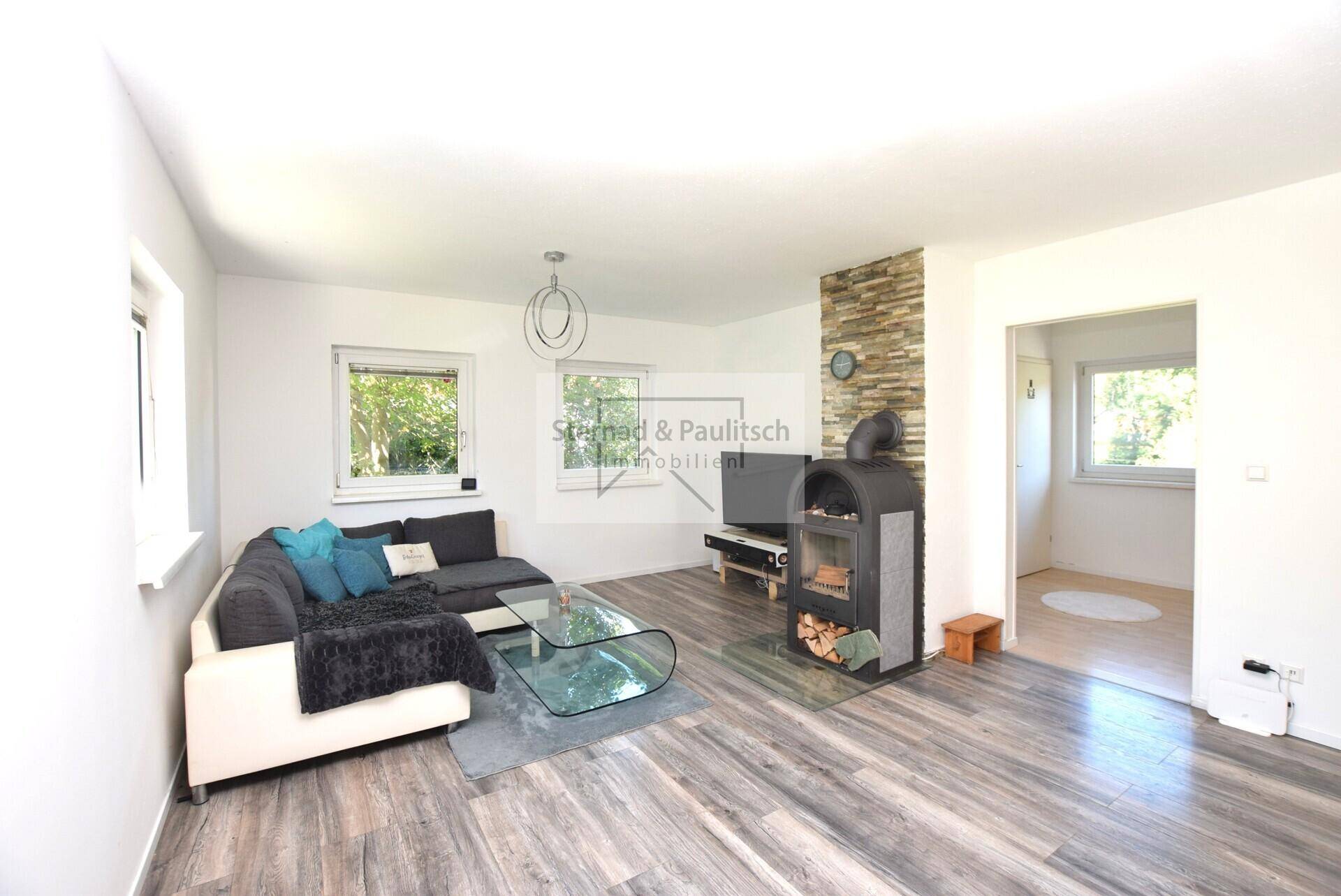 Gemütliches Wohnzimmer mit modernem Holzofen, Laminatboden und Steinwandakzent.