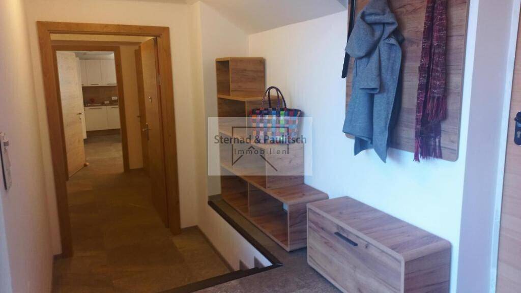 Eingangsbereich mit Holzgarderobe, Regalen und Treppenabgang, praktisch und gut organisiert.
