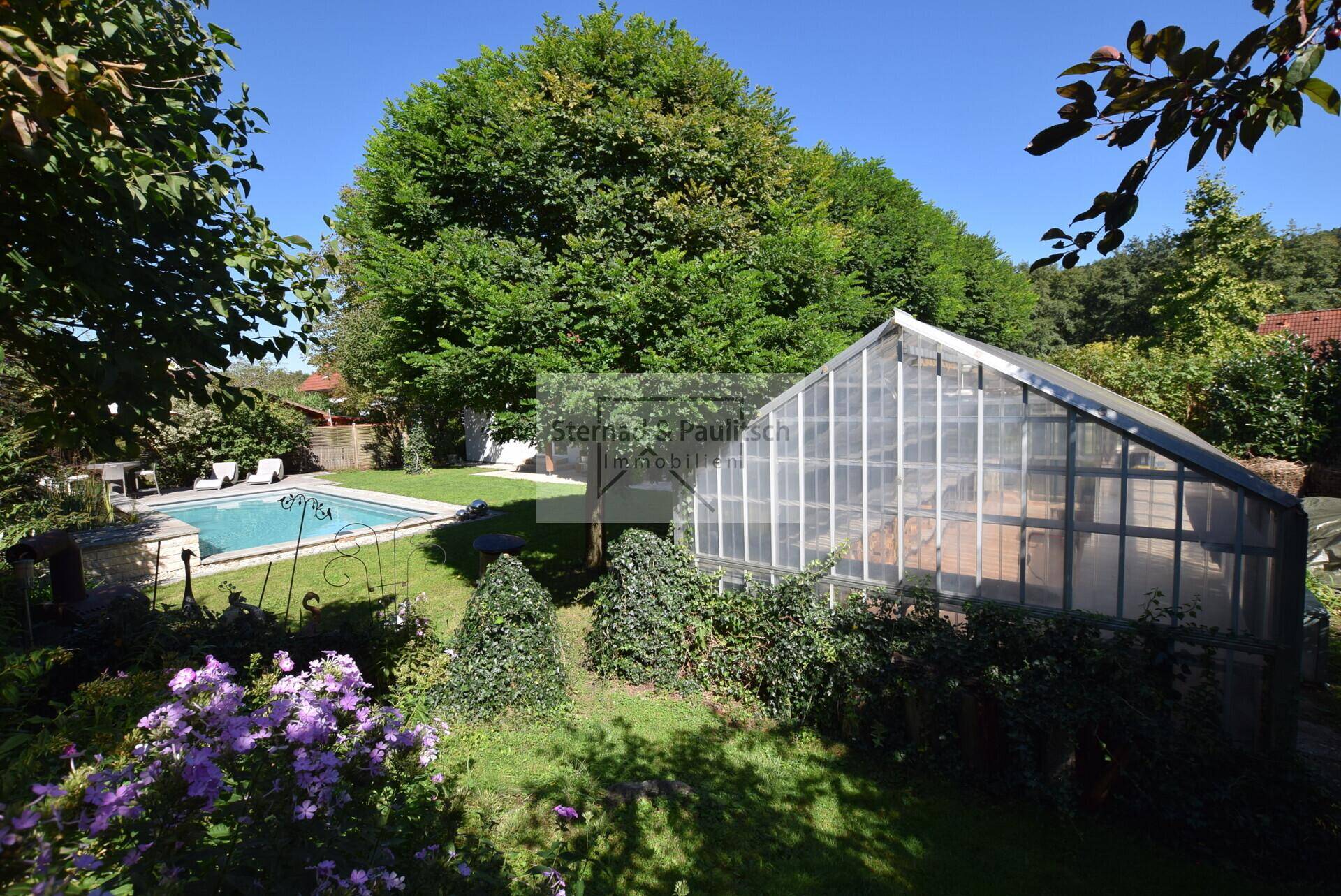 Großer Garten mit Gewächshaus, Poolbereich und altem Baumbestand.