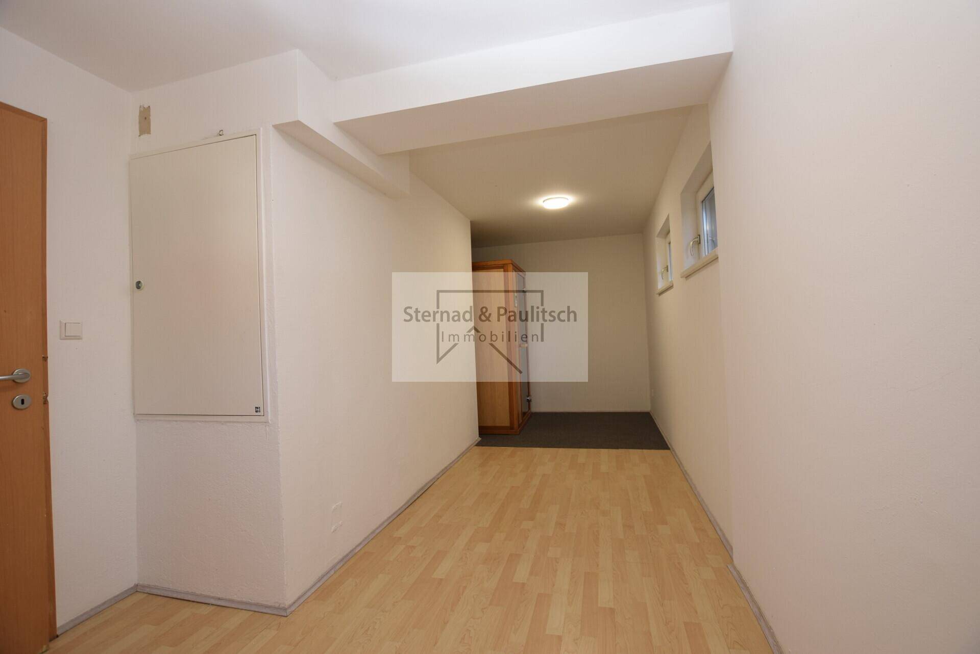 Heller Flur mit Holzboden und Zugang zu weiteren Räumen.