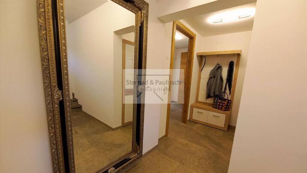 Heller Eingangsbereich mit großem Spiegel und Garderobe für Jacken und Taschen.