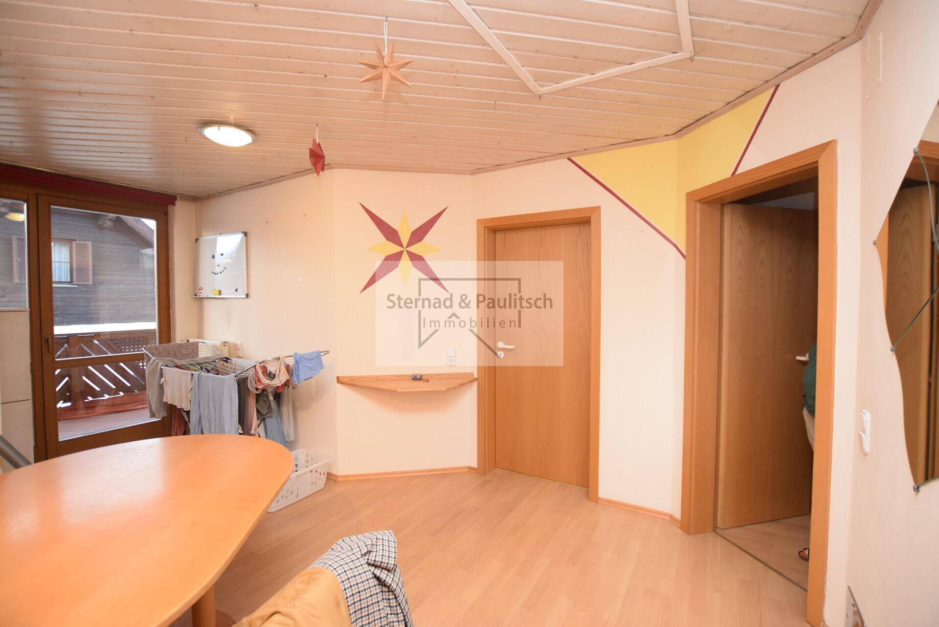 Heller Raum mit Holzbalkendecke, Holzboden und Zugang zu einem Balkon, vielseitig nutzbar.