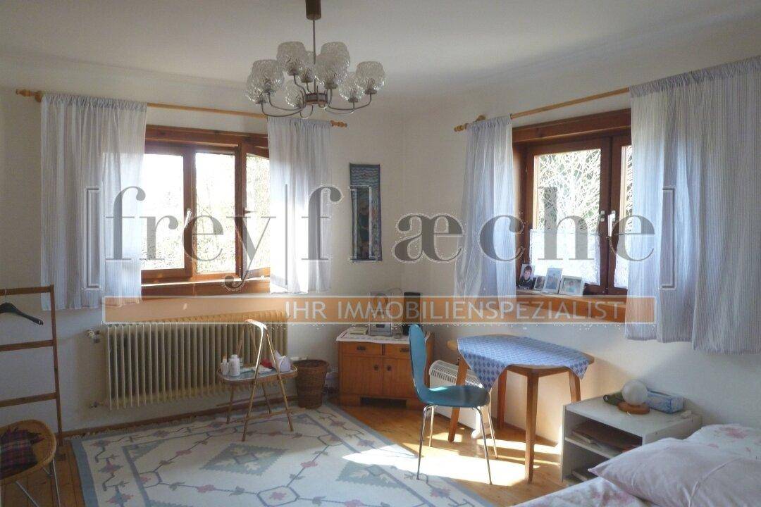 Helles Schlafzimmer mit zwei Fenstern, Teppichboden und traditioneller Einrichtung.