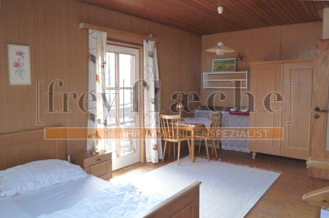 Rustikales Schlafzimmer mit Holzwänden, Holzboden und Zugang zu einem Balkon.