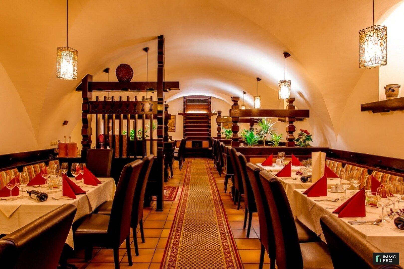 Gemütlicher Restaurantbereich mit gewölbter Decke, Holzelementen und langen Tischreihen für Gäste.