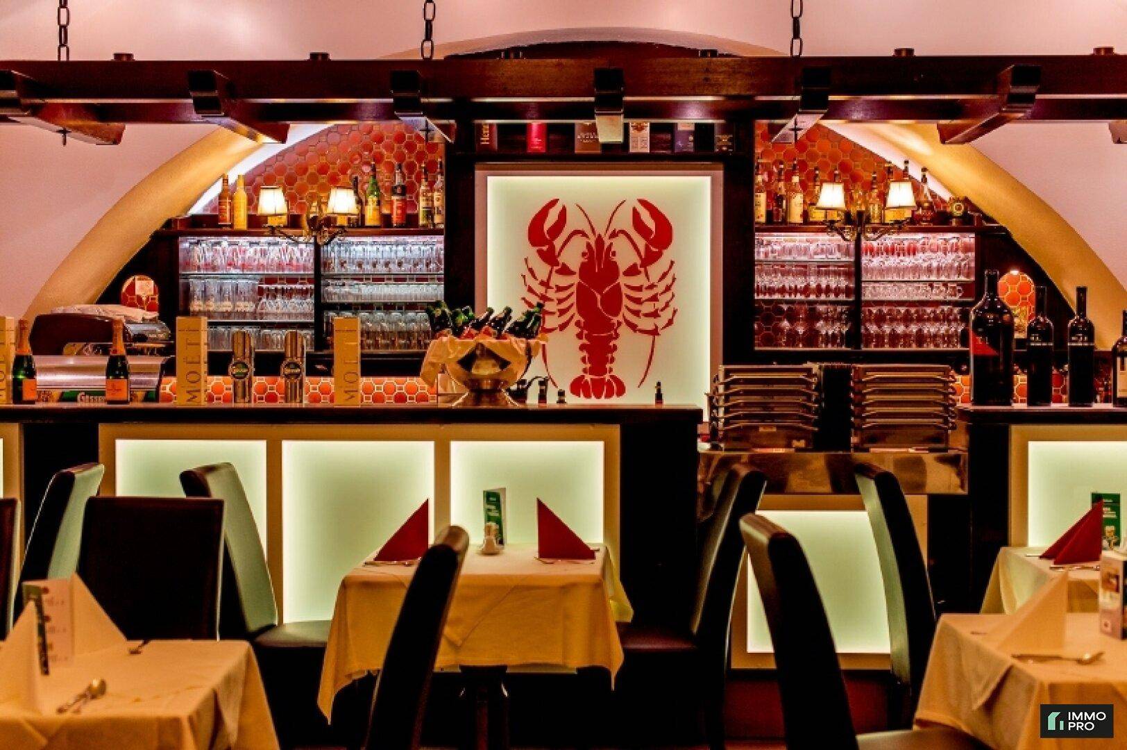 Elegante Restaurantbar mit beleuchteter Theke, Hummer-Logo und gut sortierten Getränkeregalen.