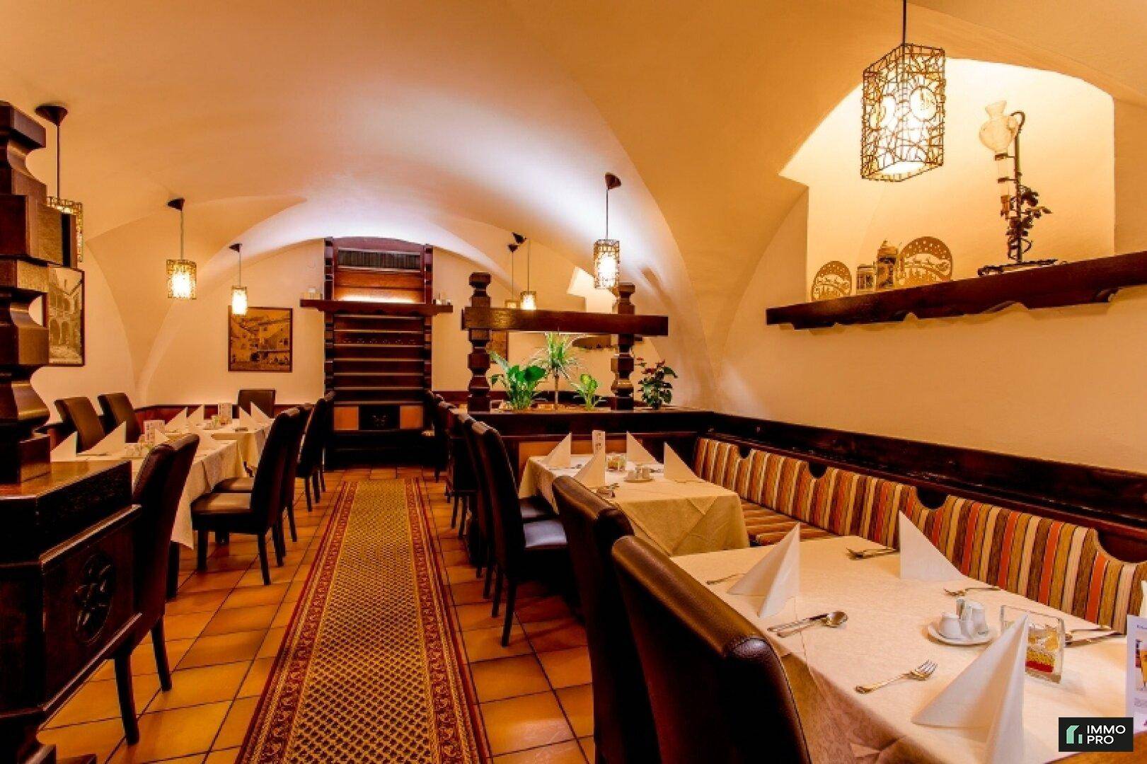 Langer Restaurantraum mit bequemen Sitzbänken, Holzelementen und dekorativen Wandleuchten.