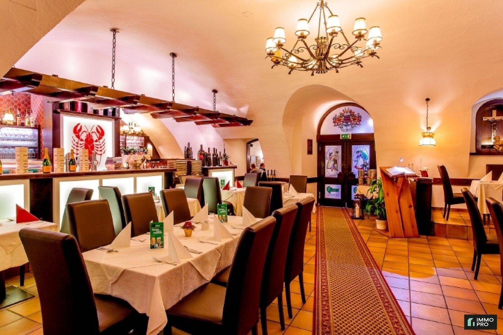 Geräumiger Restaurantbereich mit Kronleuchter, Bar und traditioneller Einrichtung, bereit für Gäste.