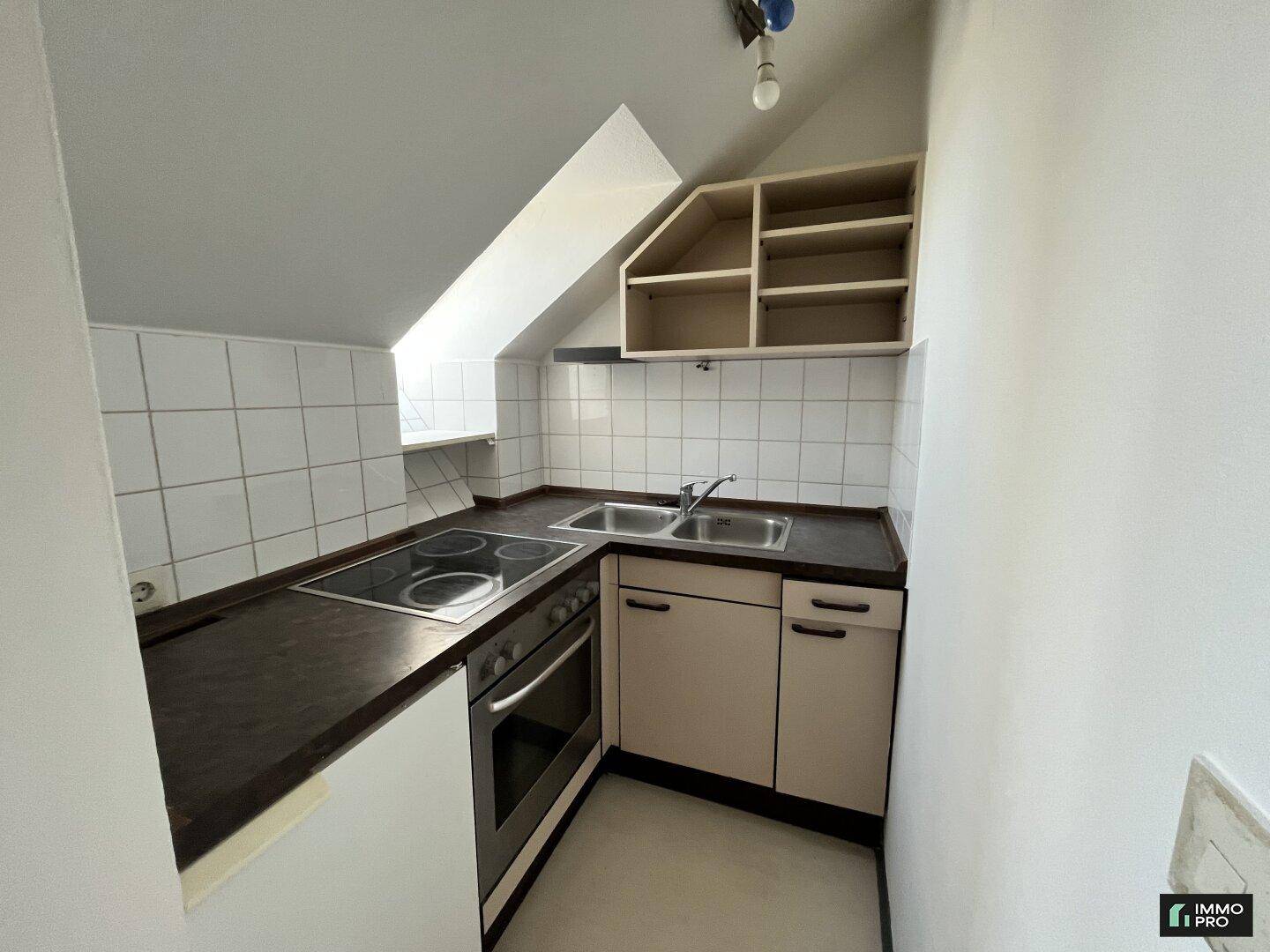 Detailansicht der kompakten Küchenzeile mit Elektroherd, Spüle und Fliesenrückwand.