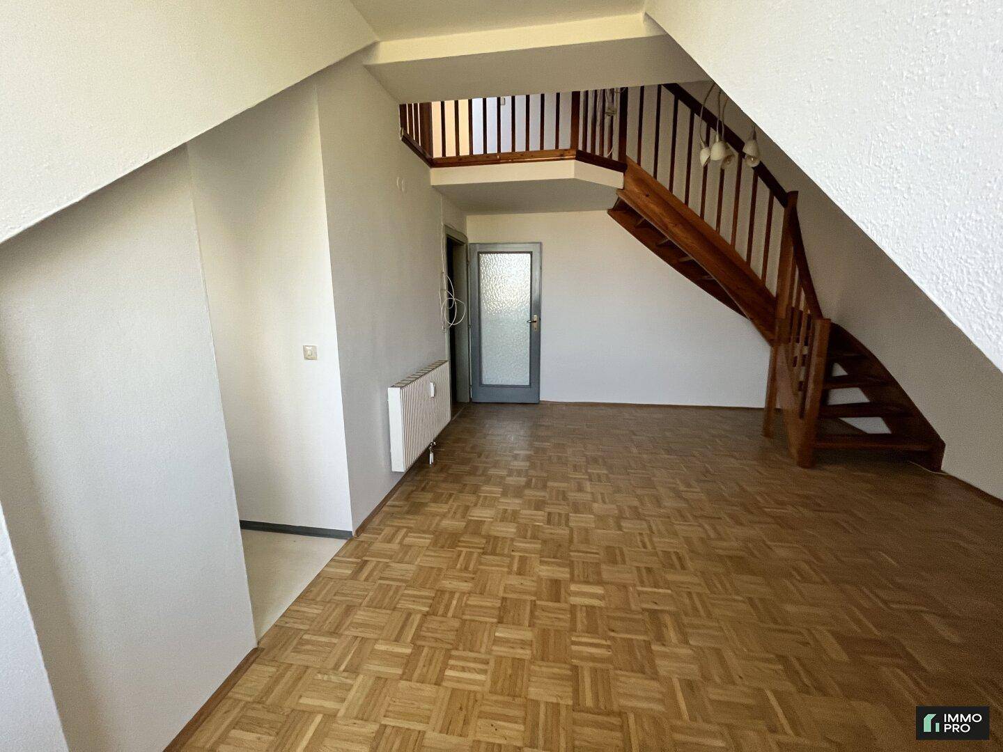 Eingangsbereich mit Holztreppe, Parkettboden und Zugang zu weiteren Räumen.