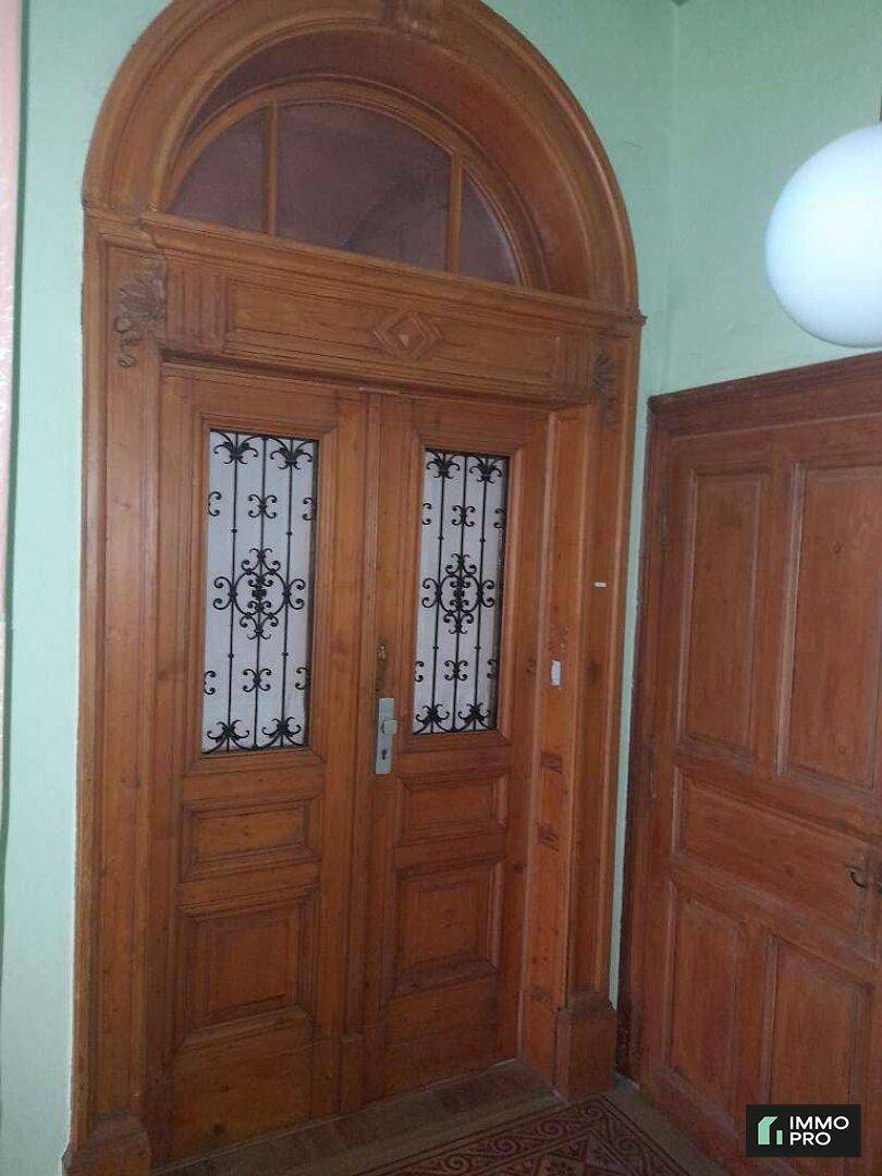 Eindrucksvolle, reich verzierte Holztür im Eingangsbereich mit Bogenfenster.