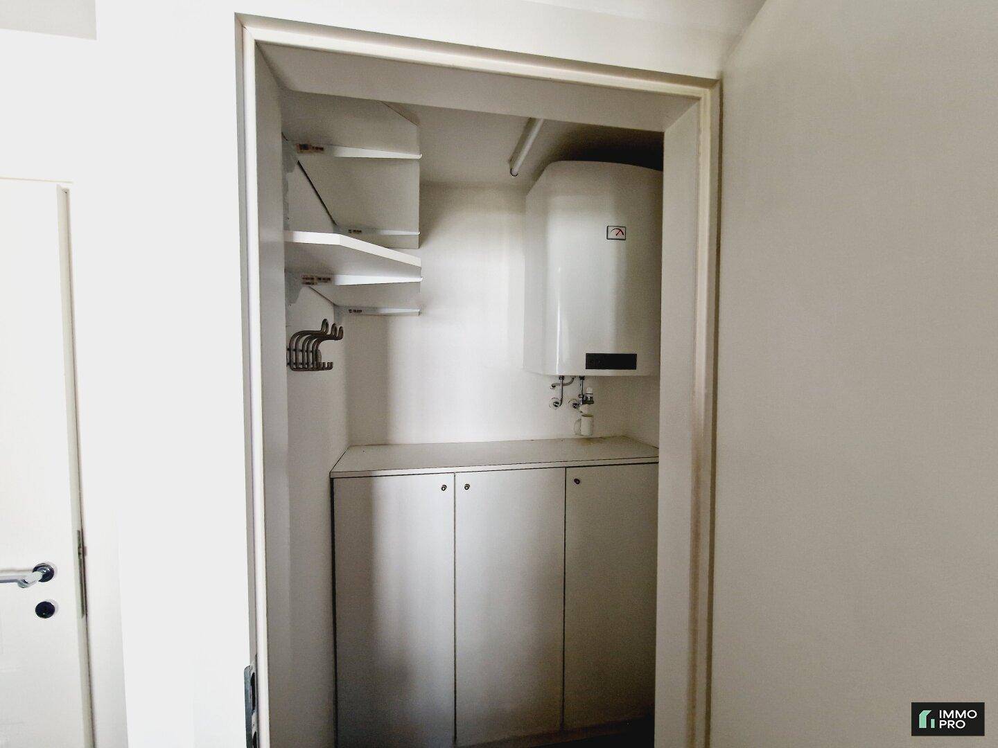 Praktischer Abstellraum mit Regalen, Schränken und einem Warmwasserboiler, ideal für zusätzlichen Stauraum.