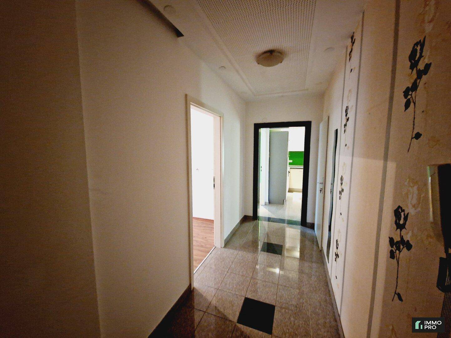 Heller Flur mit Fliesenboden, der zu den verschiedenen Räumen der Wohnung führt.
