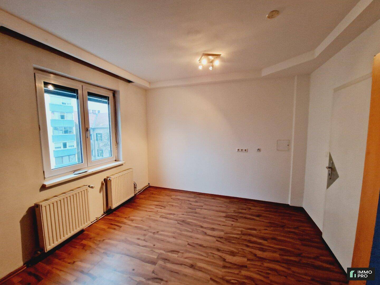 Geräumiges Zimmer mit Laminatboden und großem Fenster, ideal als Schlaf- oder Arbeitszimmer.
