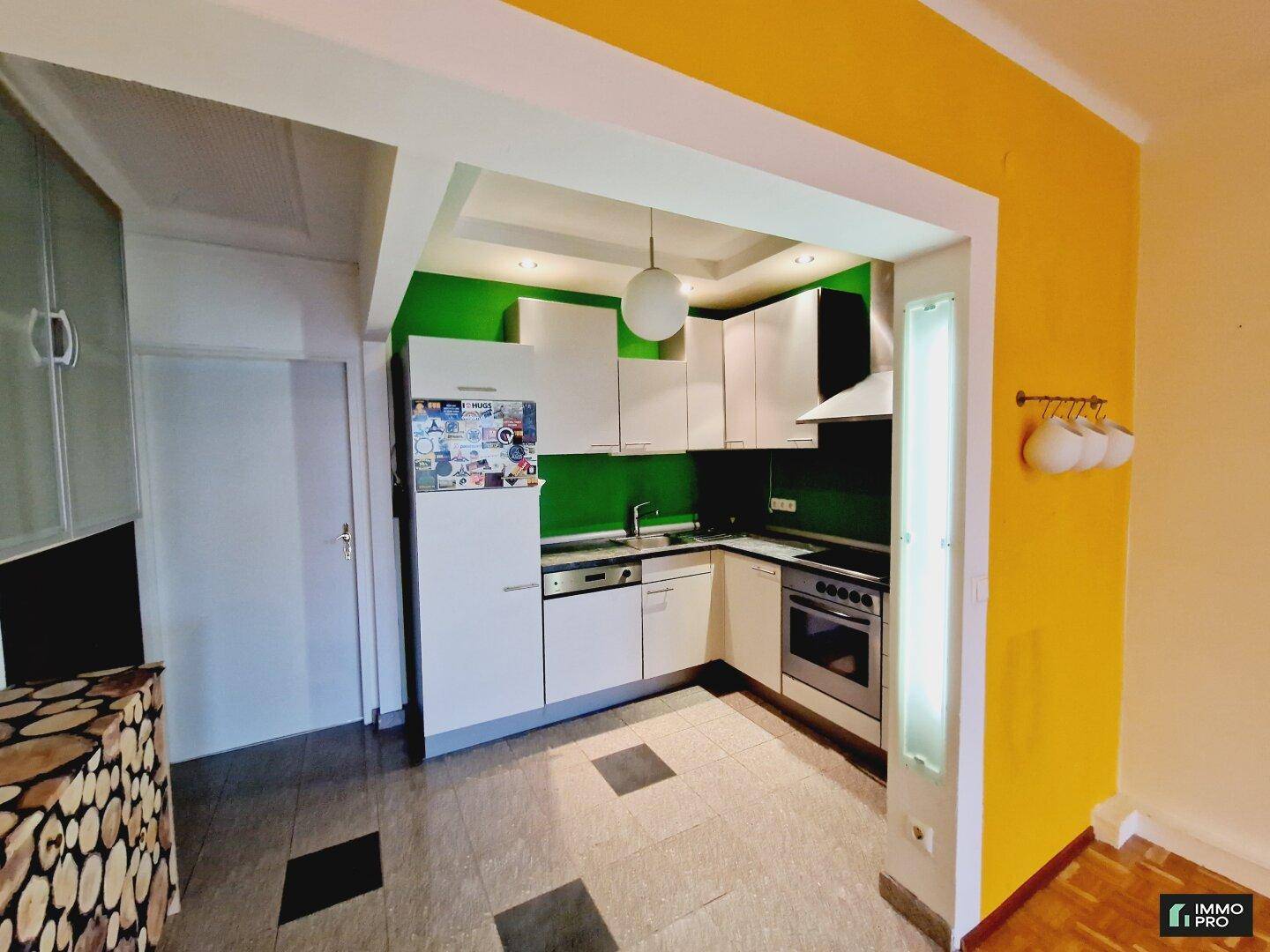 Funktionale Küche mit weißen Schränken, grüner Wand und integrierten Haushaltsgeräten.