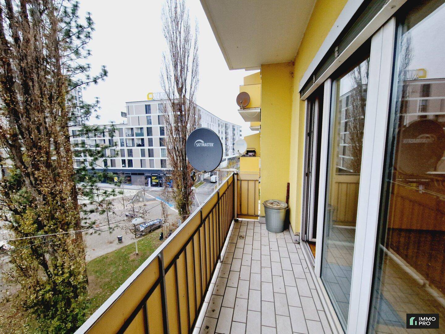 Langer Balkon mit Fliesenboden und Blick auf die Straße und die umliegenden Gebäude.