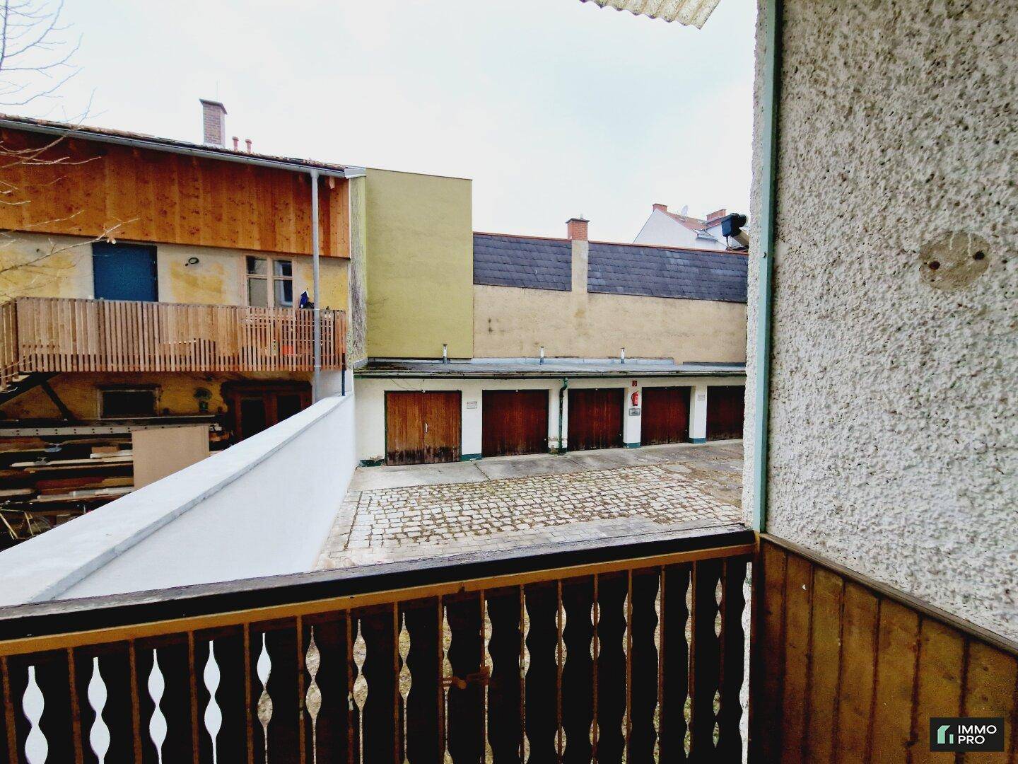 Blick vom Balkon auf einen Innenhof mit Garagen und umliegenden Gebäuden, bietet eine praktische Aussicht.