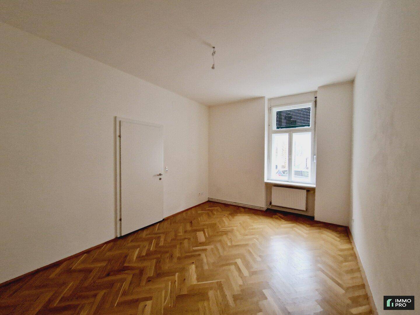 Gemütliches Zimmer mit Fischgrätparkett, weiß gestrichenen Wänden und einem Fenster, ideal für ein Schlafzimmer.
