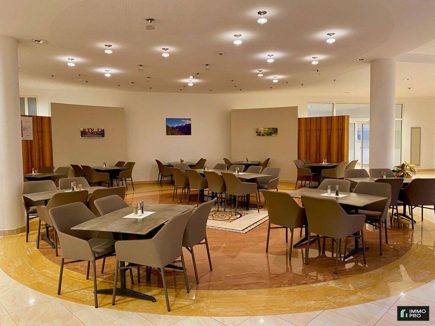 Großer Speisesaal oder Kantine mit zahlreichen Tischen und Stühlen, ideal für Veranstaltungen.