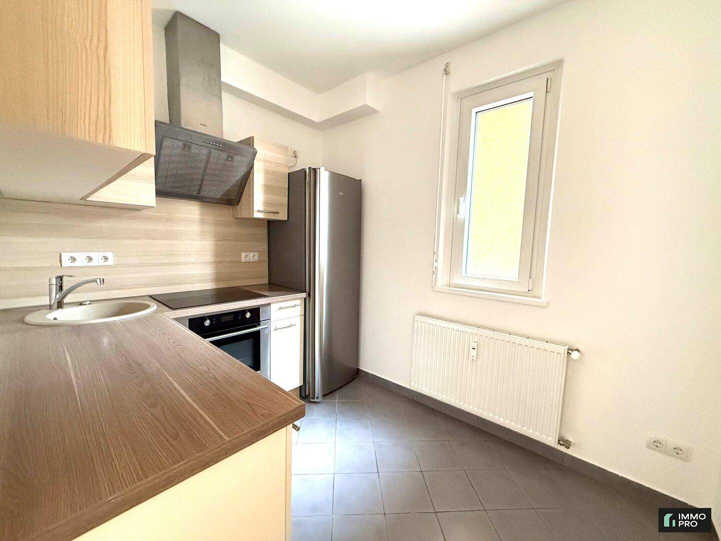 Funktionale Küche mit Fenster, ausgestattet mit modernen Geräten und praktischen Arbeitsflächen.